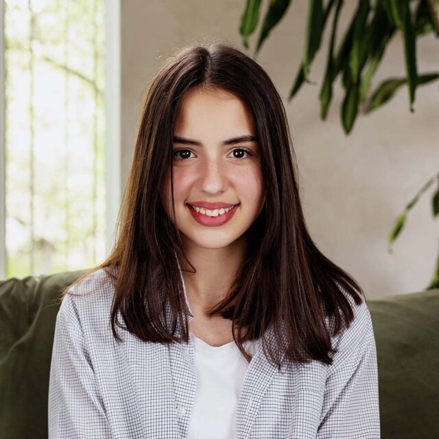 Beautiful smiling caucasian girl sitting at green 5b76at2.jpg